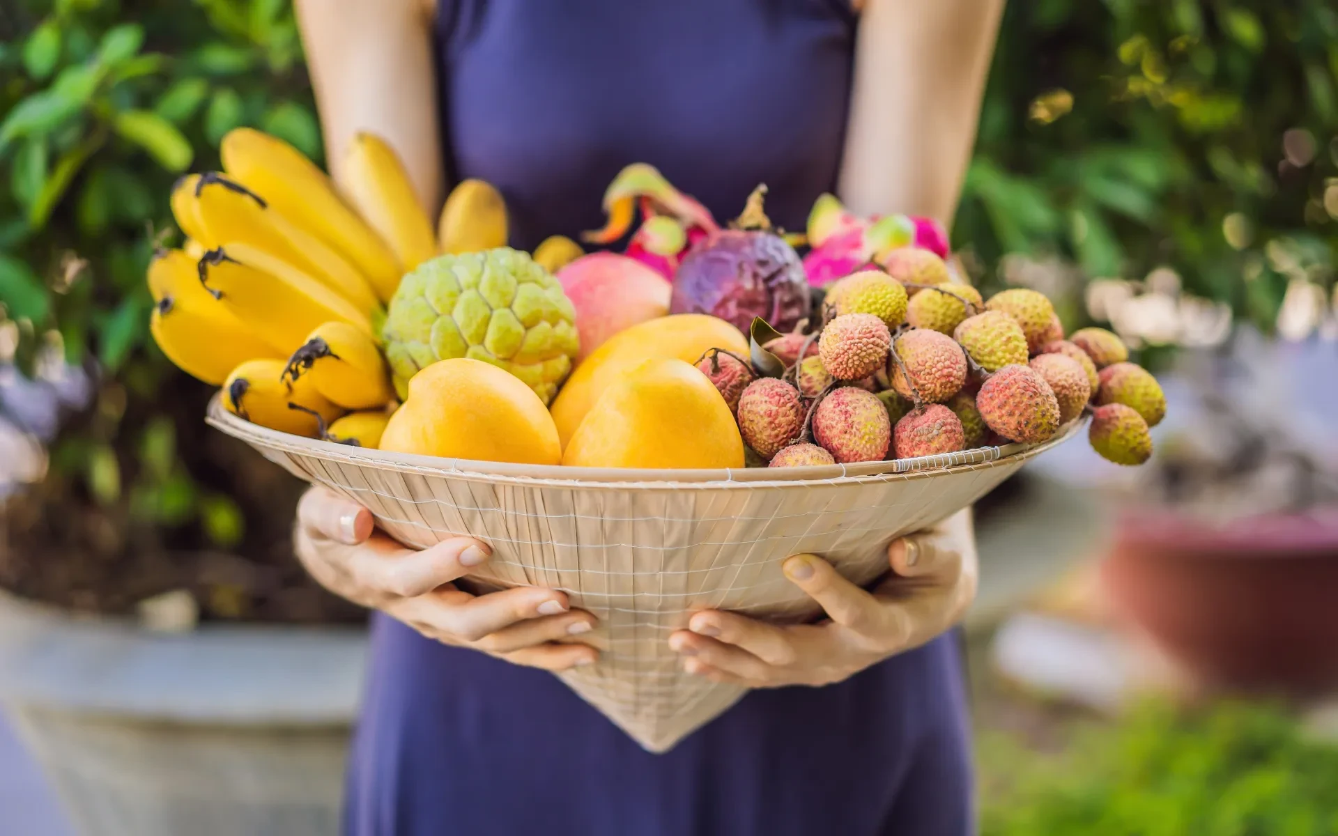 Woman holds a variety of tropical fruits and vegetables in 2025